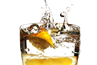 水が入った透明なグラスにレモンを入れ落とす