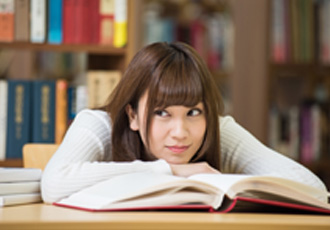 女性が本の上で顎を乗せている