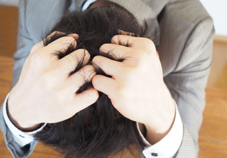 頭を抱えていく男性の頭上